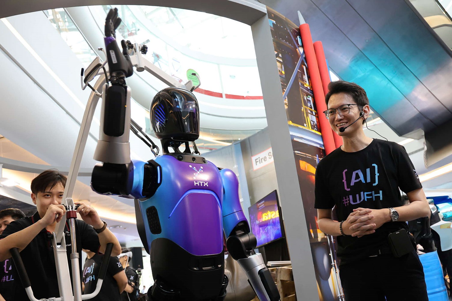 A HTX officer standing next to a humanoid robot at an exhibition.