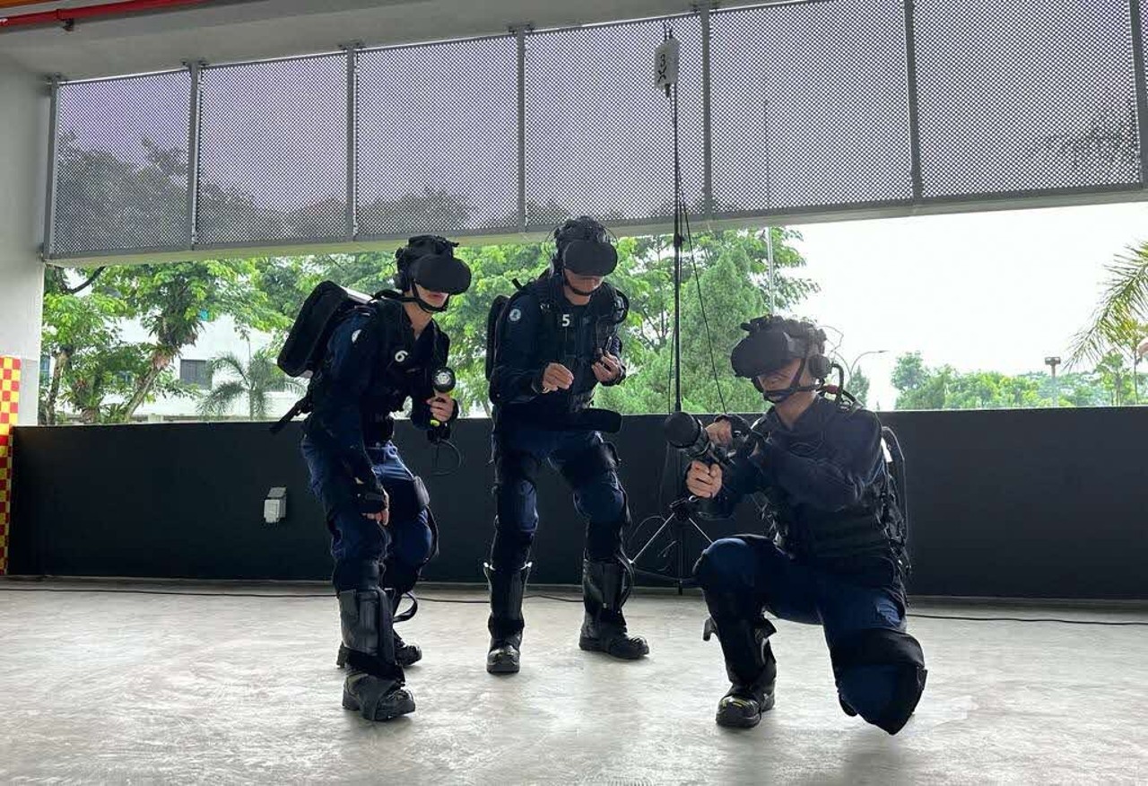 A group of people in dark blue uniforms wearing headsets and carrying equipment backpacks.