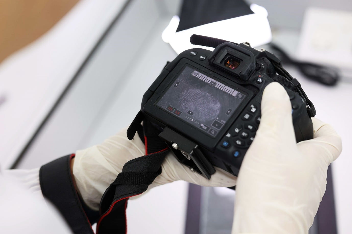A person holding a camera with a fingerprint and scale on its screen.