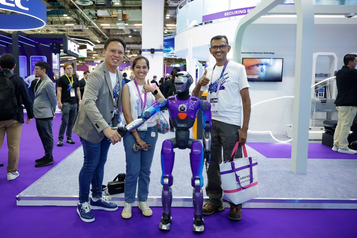 Three people posing with HTX's humanoid robot.